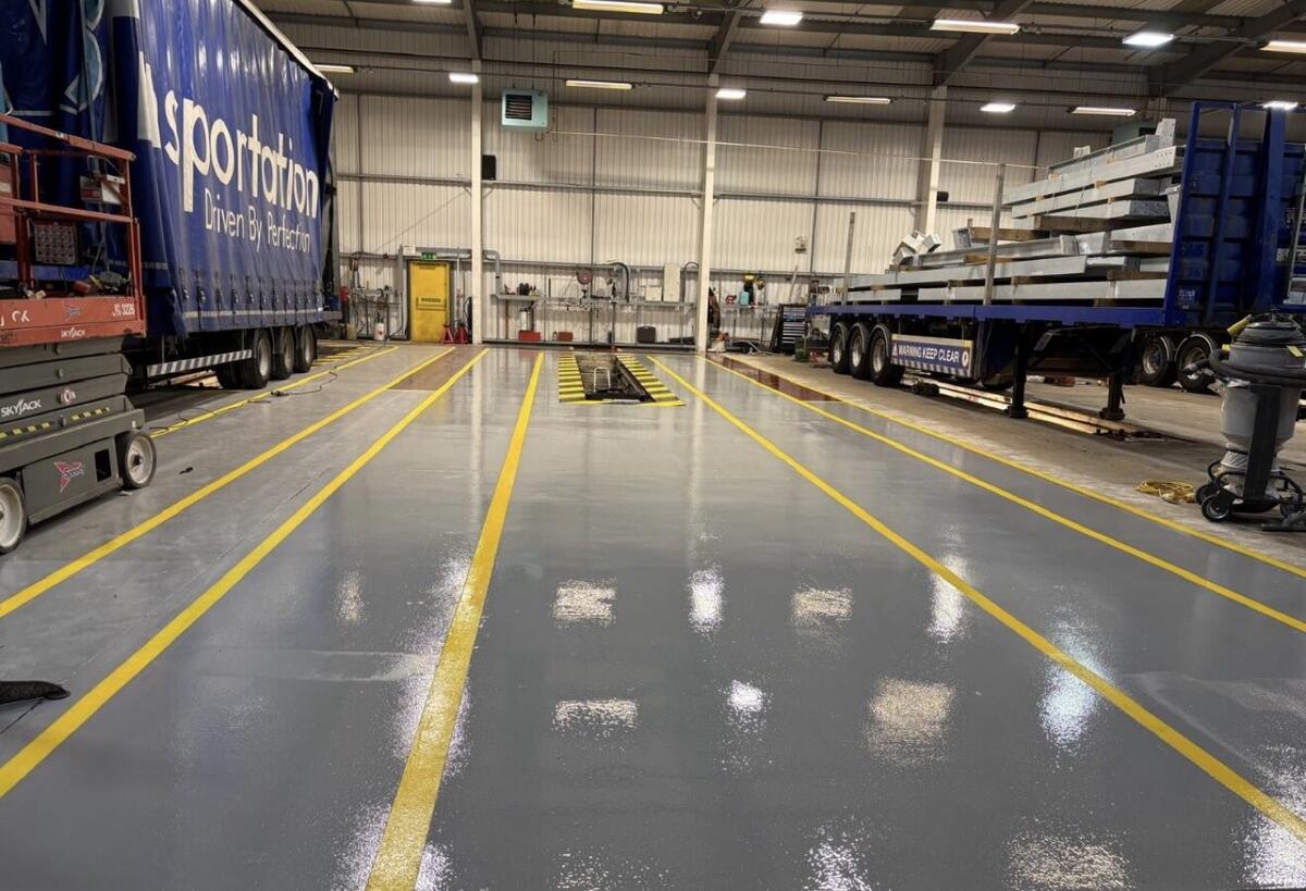 Freshly coated grey resin warehouse floor with yellow lane markings by C&R
